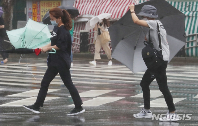 인천 미추홀구 인천터미널역 사거리에서 지난 20일 시민들이 바람에 날리는 우산을 잡고 횡단보도를 건너가고 있다.