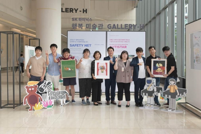 (사진=SK하이닉스) 기념식에 참석한 SK하이닉스 관계자와 ‘오티스타’ 소속 자폐인 디자이너들이 사진을 찍고 있다. 왼쪽 다섯 번째부터 오티스타 이소현 대표, SK하이닉스 이일우 EE담당