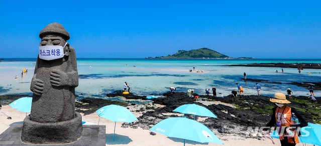 지난 17일 제주시 한림읍 금능해수욕장에 설치된 돌하르방에 방역수칙 준수를 강조하는 마스크가 씌워져 있다. 휴가철을 맞아 제주에 여행객이 몰리는 가운데 최근 신종 코로나바이러스 감염증(코로나19) 확진자가 잇달아 발생해 방역에 비상이 걸렸다.