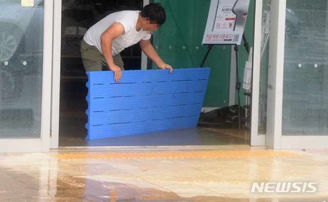 지속적인 장마가 이어지며 전북지역에 호우경보가 내린 지난 30일 전북 전주시 완산구 효자동의 한 의류매장이 빗물에 잠기자 매장 관계자가 가게에서 물을 빼내고 있다.