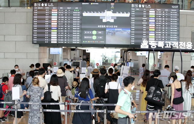 본격적인 휴가철을 맞은 지난달 31일 오전 서울 강서구 김포공항 국내선 청사에서 여행객들이 탑승장에서 줄을 서 있다. 1일 전문가들은 8월 이후 가을~겨울엔 코로나19와 증상 구분이 어려운 계절 독감이 유행하는 시기여서 전파 위험도를 최대한 낮춰야 한다고 주장했다.