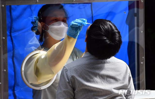 부산기계공고 2학년 학생 3명이 신종 코로나바이러스 감염증(코로나19) 확진 판정을 받은 가운데 13일 오후 해운대구 해당 학교에 마련된 선별진료소에서 한 교직원이 진단검사를 위한 검체를 채취하고 있다. 부산시는 부산기계공고 학생과 교직원 982명을 대상으로 전수검사를 시행키로 했다.