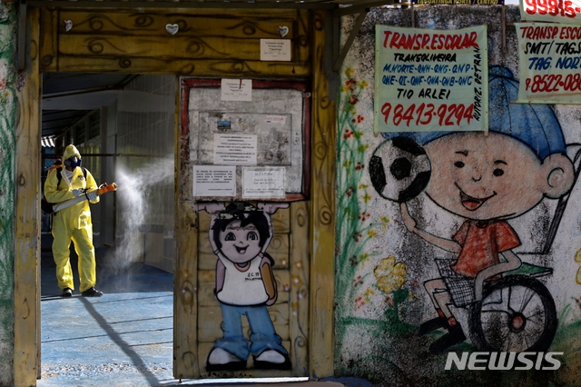 지난 7월 28일(현지시간) 브라질 수도 브라질리아 타구아팅가 인근 지역에서 한 공무원이 코로나19 방역 대책으로 한 공립학교를 소독하고 있다. 브라질의 코로나19 누적 확진자 수는 248만4649명이고 사망자는 8만8634명이다.