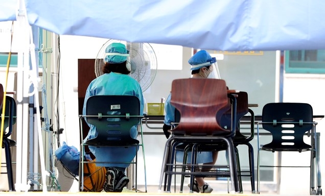 서울 강남구 보건소에 마련된 신종 코로나바이러스 감염증(코로나19) 선별진료소에서 방진복을 입은 의료진이 대기하며 선풍기 바람을 쐬고 있다.