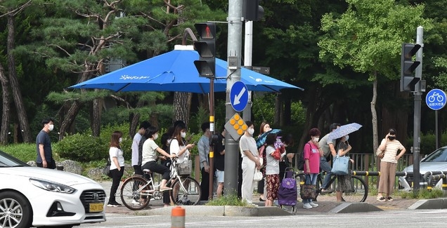폭염이 기승을 부린 지난 20일 오후 경기 안산시 단원구 고잔동 거리에서 시민들이 그늘막 아래 모여 신호를 기다리고 있다.