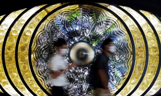 27일 일본 도쿄에서 코로나19 확산 예방을 위해 마스크를 쓴 행인들이 설치 예술 작품 앞을 지나고 있다.