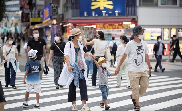 지난 17일 일본 도쿄 신주쿠의 한 횡단보도를 마스크를 쓴 가족이 건너고 있다.