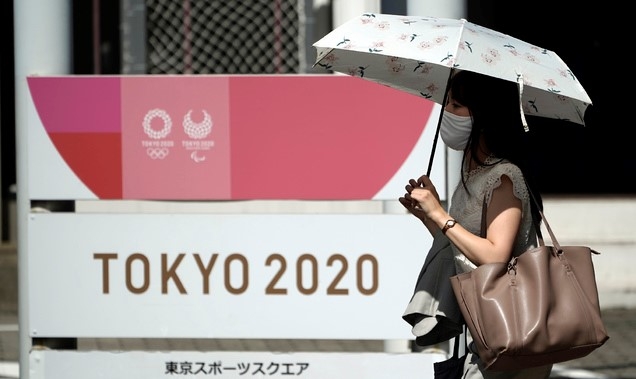 4일(현지시간) 일본 도쿄에서 한 여성이 신종 코로나바이러스 감염증(코로나19)을 막기 위해 마스크를 쓴 채 도쿄 올림픽 광고판 앞을 지나가고 있다.