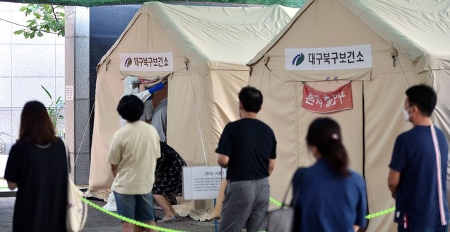 지난달 29일 대구 북구 소재 동우빌딩 지하1층에서 열린 동충하초 사업설명회가 코로나19 확산지로 지목되고 있는 가운데 4일 오전 대구 북구 침산동 북구보건소에 마련된 코로나19 선별진료소를 찾은 시민들이 검사를 받기 위해 줄을 서 있다.