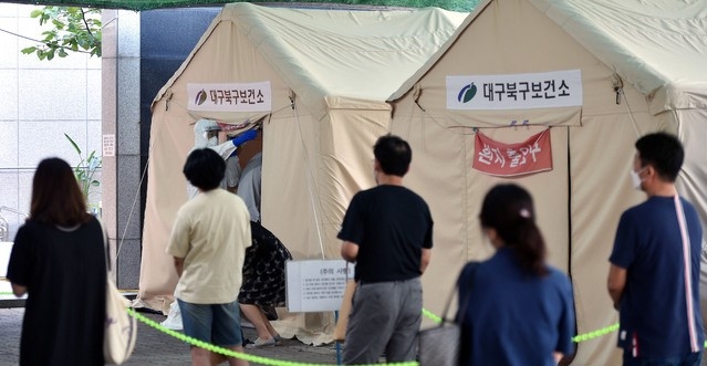 지난달 29일 대구 북구 소재 동우빌딩 지하1층에서 열린 동충하초 사업설명회가 코로나19 확산지로 지목되고 있는 가운데 4일 오전 대구 북구 침산동 북구보건소에 마련된 코로나19 선별진료소를 찾은 시민들이 검사를 받기 위해 줄을 서 있다.