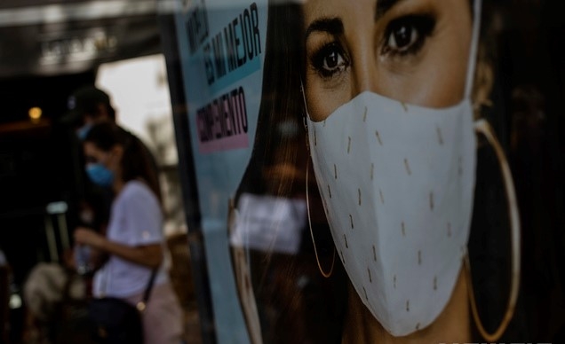 지난달 31일(현지시간) 스페인 마드리드에서 마스크를 쓴 행인들이 한 광고판 앞을 지나고 있다.