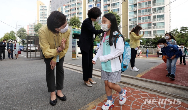 수도권 지역 학교들이 전면 원격수업을 끝내고 등교수업을 재개한 21일 오전 서울 강동구 한산초등학교를 방문한 유은혜 사회부총리 겸 교육부 장관이 등교하는 학생들과 인사를 나누고 있다.