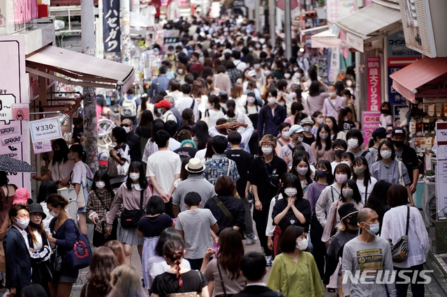 지난 21일 일본 도쿄의 한 상가에서 신종 코로나바이러스 감염증(코로나19) 예방을 위해 마스크를 착용한 사람들이 걷고 있다. 