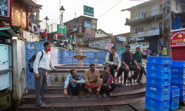 23일(현지시간) 인도 다람살라에서 코로나19 확산 방지를 위해 마스크를 쓴 일용직 노동자들이 길가에 앉아 일거리를 기다리고 있다.