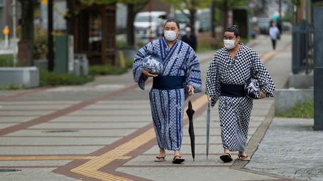 ]지난 24일 일본 도쿄 료고쿠 국기관 앞을 마스크를 쓴 스모 선수들이 걷고 있다.