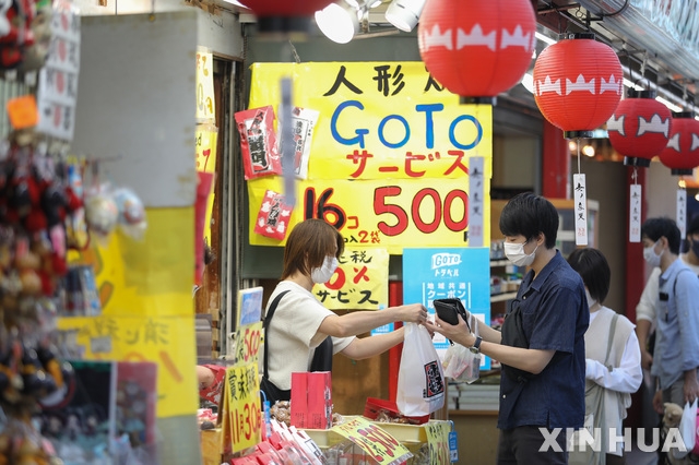 일본 도쿄 중심에 있는 아사쿠사 상점가에서 코로나19 예방을 위해 마스크를 착용한 손님들이 물건을 사고 있다.