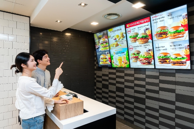 (사진=삼성전자) 삼성전자 모델이 경기도 고양시에 위치한 맥도날드 고양삼송DT점에 설치된 삼성 스마트 사이니지를 소개하고 있다.