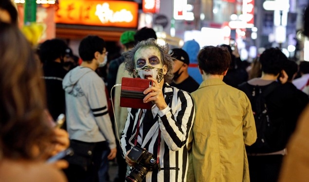 10월 31일 저녁 일본 도쿄의 시부야 거리에서 핼러윈 분장을 한 한 남성이 사진을 찍고 있다. 이날 시부야 거리에 핼러윈을 즐기려는 수천 명이 몰려들었으며 시 당국은 코로나19 확산 우려로 사람들에게 모이지 말 것을 요청했다.