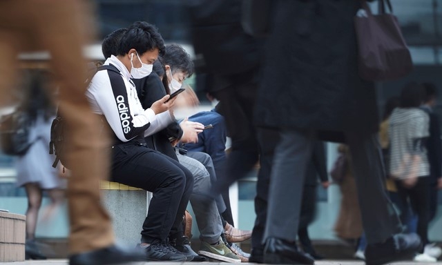 지난 20일 일본 도쿄에서 출근 시간에 신종 코로나바이러스 감염증(코로나19) 확산 방지를 위해 마스크를 쓴 사람들이 한 지하철역 통로 밖 의자에 앉아 있다.