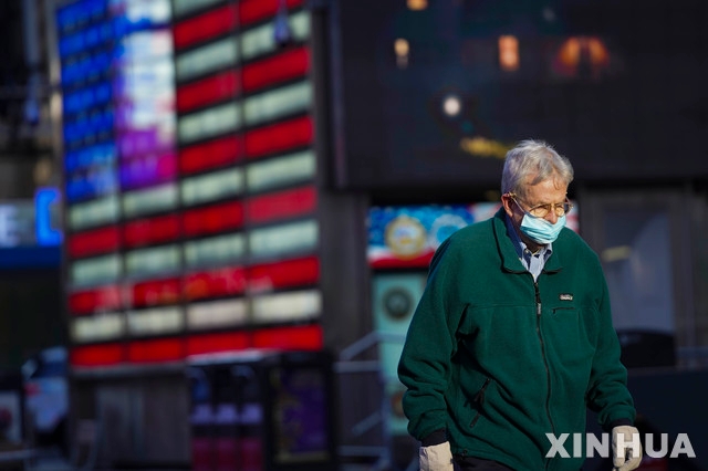 미국의 코로나 사망자가 25만명을 돌파한 18일에 이를 보도하는 뉴욕 타임스 스퀘어의 전광 뉴스판 앞을 한 남성이 마스크를 쓴채 걸어가고 있다. 존스 홉킨스대는 미국의 코로나19 확진자수가 21일 1201만명을 돌파했다고 발표했다.