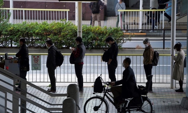 지난 20일 일본 도쿄에서 시민들이 신종 코로나바이러스 감염증(코로나19) 예방을 위해 마스크를 착용하고 출근하기 위해 버스 줄을 서 있다.