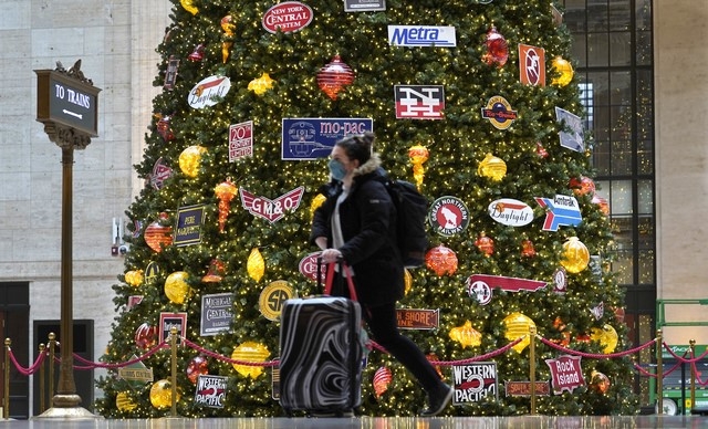 25일(현지시간) 마스크를 쓴 여행객이 미국 시카고 유니온역의 크리스마스 트리 앞을 지나고 있다. 