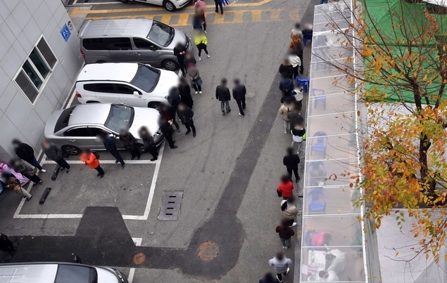 부산지역에 신종 코로나바이러스 감염증(코로나19) 확진자가 급증하고 있는 가운데 26일 오전 부산진구보건소 선별진료소를 찾은 시민들이 코로나19 진단검사를 받기 위해 길게 줄을 선 채 차례를 기다리고 있다.