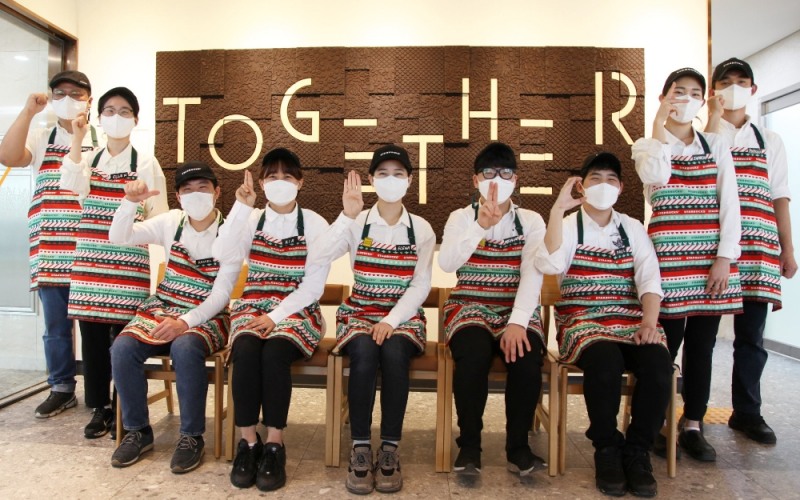 '서울대치과병원점' 파트너들이 커피찌꺼기를 재활용한 아트웍 앞에서 수어로 "s.t.a.r.b.u.c.k.s(왼쪽부터)"를 표현하고 있다. ‘TOGETHER’라는 문구의 아트웍은 모두가 함께 즐길 수 있는 공간이라는 뜻을 담고 있으며, 스타벅스 파트너들이 직접 제작에 참여함으로써 의미를 더했다./사진=스타벅스커피 코리아