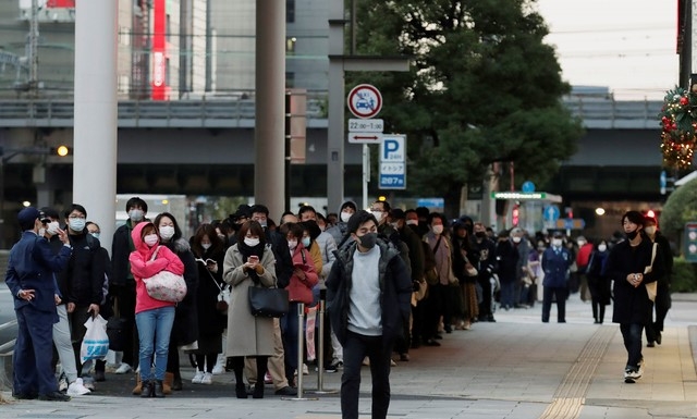 일본 도쿄에서 한 남성(가운데)이 복권을 사기 위해 줄을 서서 기다리는 사람들을 지나쳐 걸어가고 있다. 도쿄도는 코로나19 신규 확진자가 602명으로 확인됐다고 발표해 처음으로 600명을 넘으며 역대 최다를 기록했다.