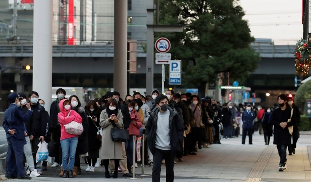 지난 10일(현지시간) 일본 도쿄에서 한 남성(가운데)이 복권을 사기 위해 줄을 서서 기다리는 사람들을 지나쳐 걸어가고 있다.