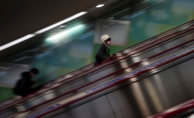 14일 일본 도쿄에서 코로나19 확산 방지를 위해 마스크를 쓴 한 여성이 에스컬레이터를 타고 있다.