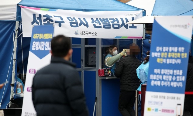 1092명의 신규 코로나19 확진자가 발생한 23일 서울 서초구 고속버스터미널 앞에 설치된 서초구 임시선별검사소에서 의료진이 검체를 채취하고 있다.