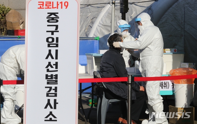 신종 코로나바이러스 감염증(코로나19)으로 열흘째 사망자수가 두 자릿수를 이어간 24일 오후 서울 중구 서울역 광장에 마련된 중구 임시 선별 검사소에서 방호복을 입은 의료진이 검체를 채취하고 있다.