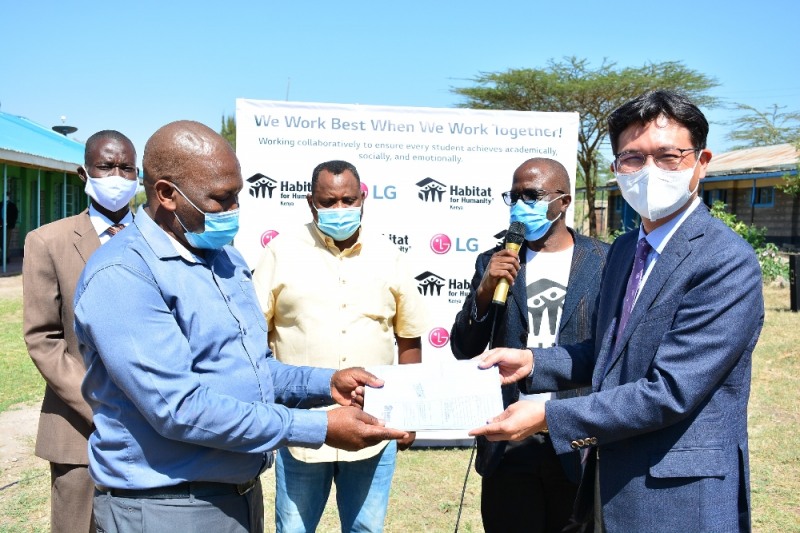 LG전자가 한국해비타트와 함께 주거 취약계층을 위한 '희망마을' 사업을 펼친다. 15일 케냐 마차코스에 위치한 쿰비 초등학교에서 LG전자 김사녕 케냐법인장(오른쪽)이 쿰비 초등학교 이사회 알바나스 회장에게 '희망마을' 사업을 위한 건축 도면을 전달하고 있다.