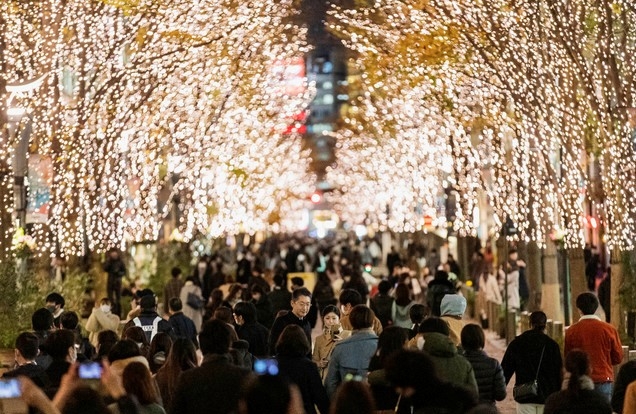 크리스마스 전날인 24일 일본 도쿄의 한 거리에서 시민들이 나무에 장식된 조명을 휴대폰으로 촬영하고 있다. 이날 일본의 신종 코로나바이러스 감염증(코로나19) 신규 확진자 수는 최다를 기록했다.
