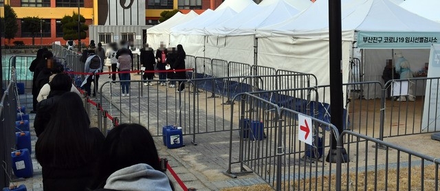 부산 부산진구 놀이마루 운동장에 마련된 신종 코로나바이러스 감염증(코로나19) 임시선별검사소를 찾은 시민들이 22일 오후 진단검사를 받기 위해 길게 줄을 선 채 차례를 기다리고 있다.