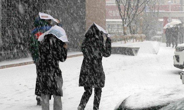 눈이 내리고 있는 12일 오후 서울 중구 하나은행 앞에서 시민들이 신문지로 눈을 막으며 이동하고 있다.
