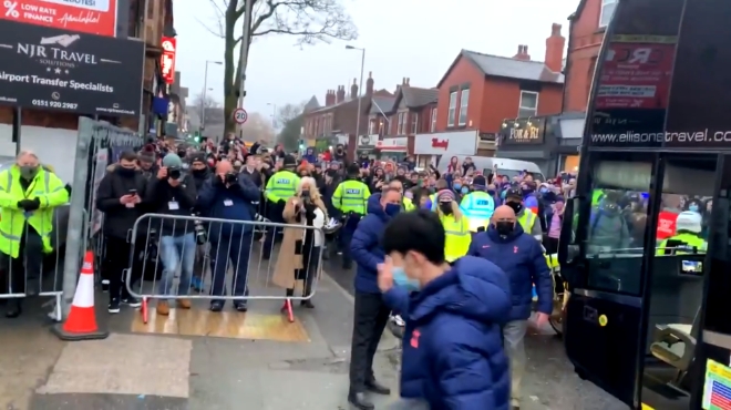 축구선수 손흥민이 구단 버스에서 내려 손을 흔들고 있다