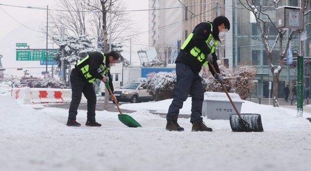 서울지역에 폭설이 내린 이튿날인 지난 13일 서울 광화문 사거리에서 서울시 관계자들이 제설작업을 하고 있다.