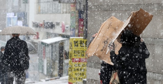 수도권을 포함한 중부지방에 눈이 내리기 시작한 지난 12일 오후 서울 서초구 인근에서 시민들이 상자를 쓰고 걸어가고 있다. 