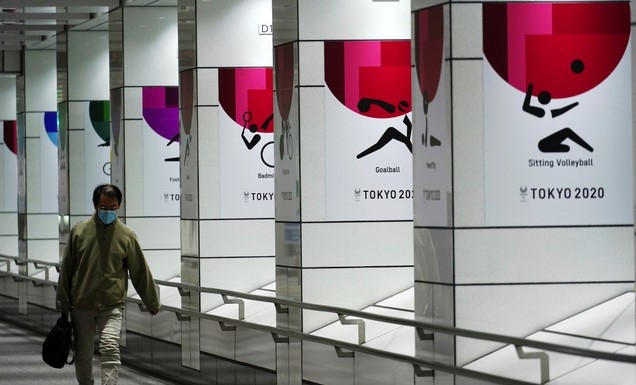 19일 코로나19 예방을 위해 마스크를 쓴 한 남성이 일본 도쿄에서 2020 도쿄올림픽 현수막 근처를 걷고 있다. 도쿄에서는 이날 1240명의 코로나19 신규 확진자가 보고됐다.