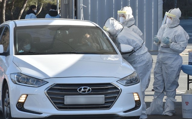 국내 신종 코로나바이러스 감염증(코로나19) 첫 확진자 발생 1년을 하루 앞둔 19일 오후 대구 수성구 대구스타디움 제3주차장에 마련된 드라이브스루 코로나19 임시선별검사소에서 의료진이 검체 채취를 하고 있다.