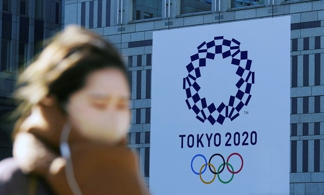 19일 코로나19 예방을 위해 마스크를 쓴 한 여성이 일본 도쿄에서 2020 도쿄 올림픽 현수막 근처를 걷고 있다. 
