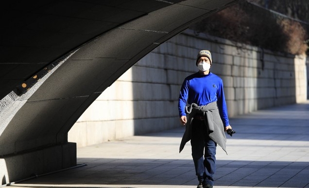 서울 지역 기온이 영상권을 회복한 지난 20일 오후 서울 청계천에서 한 시민이 외투를 입지 않고 허리에 묶은 채 걷고 있다.