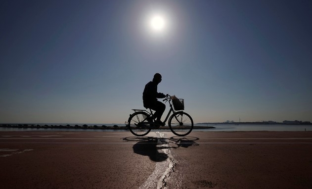 21일 일본 도쿄에서 코로나19 예방을 위해 마스크를 쓴 한 남성이 자전거를 타고 지나가고 있다.