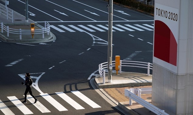 21일 일본 도쿄에서 코로나19 예방을 위해 마스크를 쓴 한 여성이 2020 도쿄올림픽 광고판 근처 건널목을 건너고 있다.