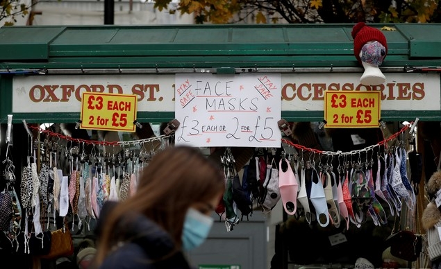 지난해 12월2일 영국 런던 옥스퍼드가의 한 가게에 신종 코로나바이러스 감염증(코로나19) 확산 억제를 위한 마스크들이 전시된 앞을 마스크를 쓴 한 여성이 지나가고 있다.