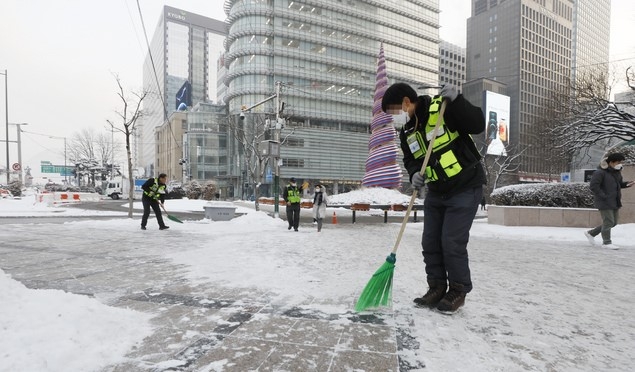 서울지역에 폭설이 내린 이튿날인 13일 서울 광화문 사거리에서 서울시 관계자들이 제설작업을 하고 있다.
