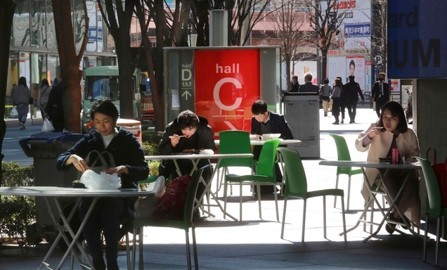 일본 수도 도쿄 시내에 있는 편의점 앞에서 16일 직장인들이 코로나19 방역 지침에 따라 거리를 두고 앉은 채 각자 도시락으로 점심식사를 하고 있다.