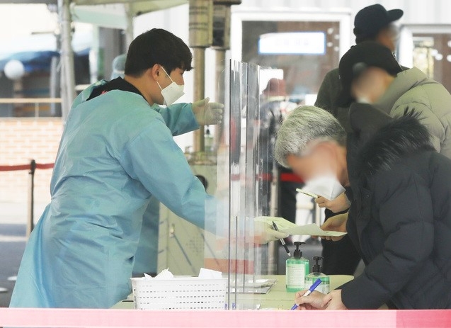 지난 21일 서울역 중구 임시선별검사소에서 시민들이 검사를 받기 위해 서류를 작성하고 있다. 